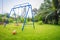 Playground equipment in the backyard for kids with soccer goal net and football on green grass field background.