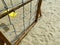 Playground. A rope flyer wall and a rocking chair with a yellow seat on the sand. Part of the playground.