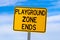 Playground Zone End Sign Against Blue Cloudy Sky