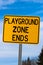 Playground Zone End Sign Against Blue Cloudy Sky and Trees