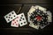 Playing cards with a winning combination of three of a kind or set and money with chips on a black vintage table. Winning in