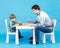 Playing chess with dad - little boy and his father on blue