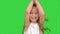 Playing, jumping little girl in white dress enjoys game on a green screen, chroma key