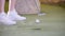 Playing mini golf. A person in white sneakers hitting the golf ball and hits the target