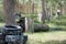 Playing in paintball. A teenager in a protective mask and camouflage clothes with arms in his hands hides behind the iron barrels