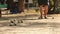 Playing Petanque in the Park - Metal Balls and Orange Wooden Ball on Rock Yard with a Man Standing in the Sun