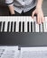 Playing the piano with one hand. Girl`s left hand on the piano keys, top view.  Stay at home