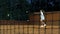 Playing tennis at night. Young girl blocking the ball with the tennis racket during the training