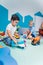 Playtime at nursery school. Toddlers boys sitting on the floor and playing with colorful plastic cars, boats, planes and