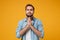 Pleading young bearded man in casual blue shirt posing isolated on yellow orange wall background studio portrait. People