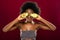 Pleasant afro American woman putting avocado halves to her eyes