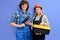 Pleasant architects in uniform coveralls stand with tools instruments posing isolated on blue