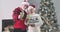 Pleasant Caucasian old couple in Christmas hats holding glasses, looking at camera and smiling. Happy spouses spending