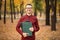 Pleasant cheerful handsome realtor holding folder and expressing positivity while standing in autumn park