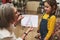 Pleasant elderly Caucasian woman tailor, caring and loving granny smiles admiring the clothes sketch of her adorable granddaughter