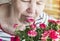 A pleasant elderly woman rejoices at the roses ,inhaling their aroma