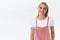 Pleasant, friendly-looking happy smiling young joyful blond girl in pink trendy overalls, t-shirt, grinning and gazing