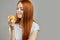 Pleasant ginger woman in white T-shirt is tasting the fruit