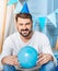 Pleasant man in party hat posing with balloon