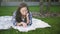 Pleasant mixed race woman is lying on the plaid and grass near campus.
