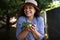 Pleasant multiethnic woman agronomist, farmer holds handful of harvested cherries and smiles sweetly, looking at camera.