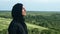 Pleasant Muslim woman breathing freedom inspiration on top of mountain over green grass forest