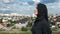 Pleasant Muslim woman in traditional black headscarf standing on mountain peak over Islamic city