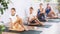 Pleasant preteen girl practicing half lord of the fishes pose of yoga with her family