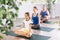 Pleasant preteen girl practicing lotus pose of yoga with her family