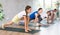 Pleasant preteen girl practicing variation of warrior pose of yoga with her family