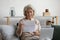 Pleasant smiling elderly mature woman reading banking loan paper notification.
