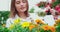 Pleasant woman watering colorful flowers at orangery