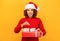 Pleasantly excited happy woman holds in hands christmas gift. woman in santa claus hat on orange background, smiling