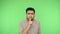 Please, be quiet, keep silent. Strict brunette man making silence gesture with finger on his lips. green background, chroma key