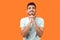 Please, I need help! Portrait of worried brunette man holding arms in prayer. isolated on orange background