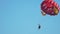 Pleased female and male athletes flying with parachute over ocean, parascending