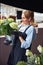 Pleased florist viewing potted flowers in her hands