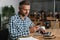 Pleased grey man using mobile phone while working with laptop