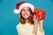 Pleased intrigued woman in sweater and christmas hat holding gift
