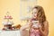 Pleased little girl drinking tea with cake