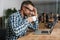 Pleased man drinking coffee while working with laptop