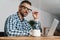 Pleased man in eyeglasses working with laptop in office