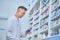 Pleased man in lab coat reviewing medications at pharmacy