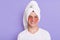 Pleased man wearing white t shirt and wrapped towel on head, expressing positive emotions, doing morning cosmetology procedures,