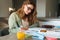 Pleased nice student woman doing homework while sitting at table