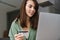 Pleased nice woman using credit card while working with laptop
