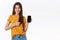 Pleased, satisfied attractive stylish girl in yellow t-shirt, showing mobile phone display, smartphone application, make