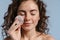 Pleased sensual shirtless girl cleaning her face with cotton pad