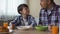 Pleased son and father eating tasty cornflakes at breakfast, morning tradition