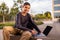 Pleased teenager using his portable computer outdoors